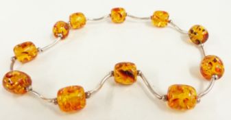 A silver necklace with pressed amber beads