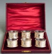Cased set of six Edward VII hallmarked silver napkin rings, with engraved foliate decoration and