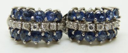 A pair of 14k white gold earrings set with a row of round cut diamonds and two rows of cornflower