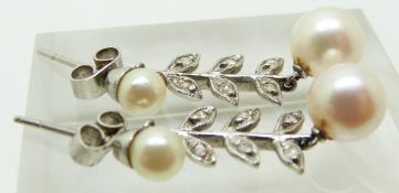A pair of white metal earrings set with two pearls and diamonds in a foliate design, 3cm long