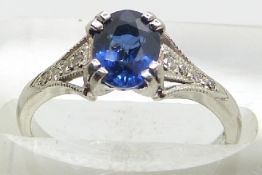 A platinum ring set with an oval cut sapphire of approximately 1ct and diamonds to the shoulders,