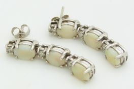 A pair of 14ct white gold earrings set with three opal cabochons to each, 4.9g