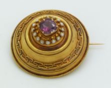 Victorian Etruscan Revival gold brooch set with a cushion cut garnet surrounded by seed pearls