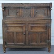 An antique country oak court cupboard with carved decoration, the top frieze carved with date, 140 x