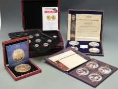 Four deluxe cased coin sets comprising commemorative gold plated and silver plated coins with enamel