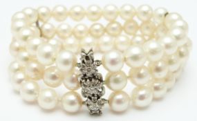 A three strand pearl bracelet with a white gold clasp set with diamonds in three clusters