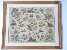 A 17thC cross stitch/embroidery decorated with flora and fauna mounted on linen in glazed frame.