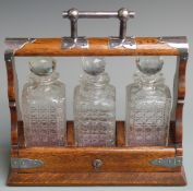 An oak three bottle tantalus with plated fittings, length 37cm