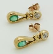 A pair of 9ct gold earrings set with an oval cut emerald and diamond to each