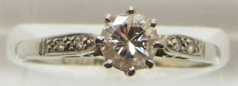 A platinum ring set with a round cut diamond measuring approximately 0.5ct, with diamond encrusted