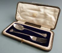 George V hallmarked silver spoon and fork christening set, decorated with winged cherub faces to