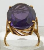 A yellow metal ring set with a large oval cut synthetic purple sapphire, 9.3g, size L