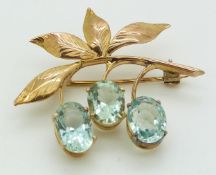 A gold brooch/ pendant set with three oval aquamarines in a foliate design, 4.9g