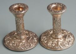Pair of hallmarked silver repoussé decorated candlesticks with vacant cartouches to stems,