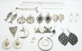 A collection of silver earrings including novelty fish and other examples and a charm bracelet