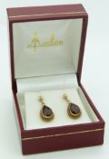 A pair of 14ct gold earrings set with a pear cut garnet to each
