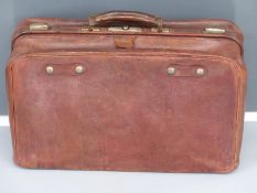 Vintage leather Gladstone bag style suitcase with filled interior and metal trim.