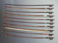 Eight round stick violin bows with various button types, together with two octagonal bows, all