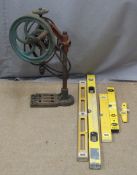 A vintage hand cranked pillar drill and five spirit levels