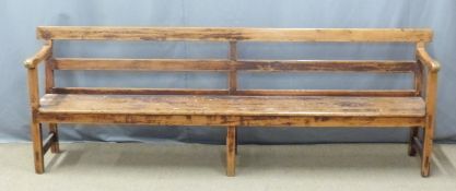 A 19thC pine pew raised on six legs united front to back by simple wooden strainers, ex Cinderford