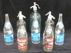 Three vintage soda siphons, two with Schweppes to front, branded club soda and other bottles