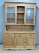 Pine dresser, the top having central shelves flanked by glazed display cupboards, the base fitted