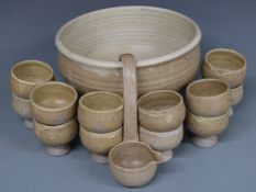 A Studio pottery punch bowl with twelve goblets and a ladle, H17cm, diameter 32cm and a slipware