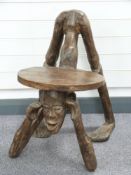 A carved tribal art wooden stool in the form of a man on all fours
