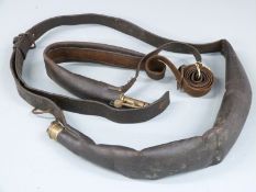 Two Bandolier type leather and brass shot flasks both with shoulder straps, largest 50cm long.