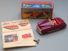 Schuco Radio 4012 clockwork tinplate car car with maroon body and red interior containing a Thorens