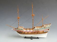 Three wooden scratch built hand painted masted sailing ships, two in display cases, largest 55cm