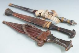 Three African/Asian tribal daggers each with leather scabbard and shaped handle, longest 36cm