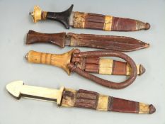Four African tribal daggers, each with leather scabbard and shaped handle