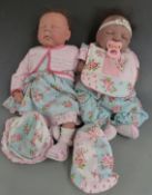 Two silicone dolls both with closed mouths and eyes, brown hair and soft bodies, one marked to the