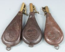 Three leather and brass shot flasks, both with embossed shooting scenes to both sides and belt