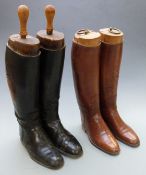 A pair of vintage black leather riding boots with wooden trees and a similar brown leather pair