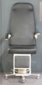 An optician's/barber's or therapist's chair with adjustable arms and footrest raised on castors,