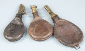Three leather and brass shot flasks, largest 24.5cm long.