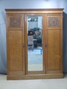 Art Nouveau carved oak wardrobe with bevelled glass mirror, interior drawers and dentil cornice, W18