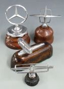 Four various car mascots including Lincoln Continental and Mercedes, all on wooden display bases,