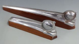 Two DeSoto car mascots formed as a man wearing a helmet, both on wooden display bases, length of