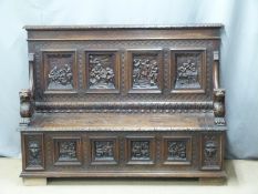 A 19thC carved oak settle, the back with four panels decorated with tavern scenes surrounded with
