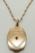 A 9ct gold locket set with a ruby on rolled gold chain