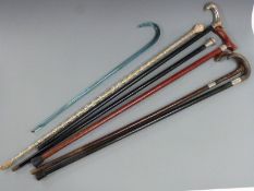 Four hallmarked silver mounted walking sticks and canes, two glass walking canes and one other