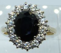 A 9ct gold ring set with an oval cut sapphire surrounded by cubic zirconia, 3.8g, size L/M