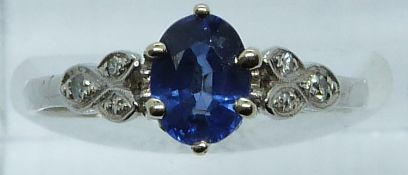A platinum ring set with an oval cut sapphire of approximately 0.65ct and diamonds to the shoulders,