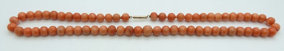 A faux coral necklace made up of glass beads with yellow metal clasp