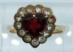 A 9ct gold ring set with a heart cut garnet surrounded by paste, 2.3g, size L/M
