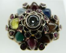 A yellow metal ring marked 18k set with a round cut diamond surrounded by pearl cut cabochons