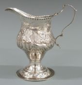 Georgian hallmarked silver pedestal cream jug with embossed decoration, marks obscured but maker's